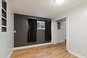 Empty room featuring light wood-type flooring, electric panel, and a textured ceiling