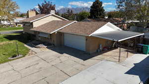 View of property exterior featuring a shingled roof, brick siding, driveway, and a mountain view