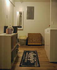 Laundry room featuring electric panel, dark wood-style flooring, and washer / clothes dryer