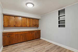 Bar featuring light countertops, brown cabinetry, a textured ceiling, and light wood-type flooring