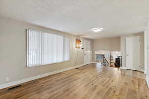 Unfurnished living room with a textured ceiling and light wood finished floors