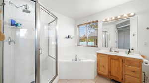 Full bath with a garden tub, light tile patterned floors, vanity, and a stall shower