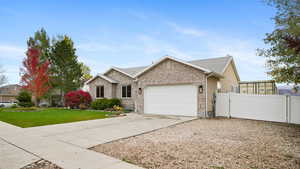 Ranch-style home with concrete driveway, a garage, brick siding, and a gate