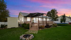 Rear view of property featuring a fenced backyard, a fire pit, a trampoline, and an outdoor structure