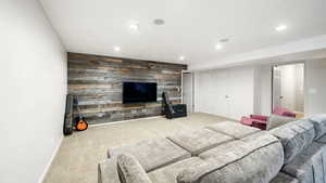 Carpeted living room featuring wood walls, recessed lighting, and an accent wall