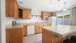 Kitchen with white appliances, a kitchen island, tile countertops, open shelves, and decorative light fixtures