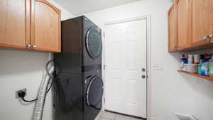 Laundry area with cabinet space, light tile patterned floors, and estacked washer and dryer