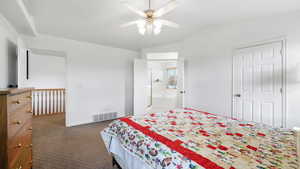 Bedroom featuring vaulted ceiling, dark colored carpet, a ceiling fan, and connected bathroom