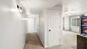 Hallway featuring light colored carpet and baseboards