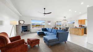 Living room with light tile patterned floors, recessed lighting, a brick fireplace, a ceiling fan, and high vaulted ceiling