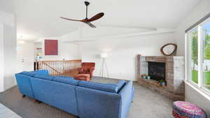 Living room with vaulted ceiling, a brick fireplace, light carpet, and a ceiling fan