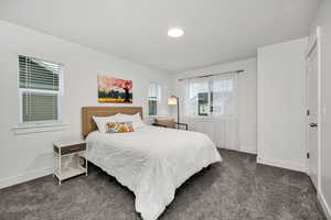 Bedroom with dark colored carpet and baseboards