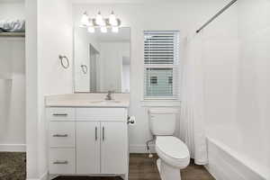 Bathroom with vanity, shower / bathtub combination with curtain, and dark wood-style floors