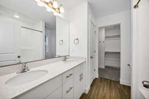Bathroom featuring dark wood-type flooring, double vanity, a walk in closet, and a shower with shower curtain