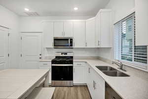 Kitchen featuring appliances with stainless steel finishes, light wood finished floors, white cabinets, and recessed lighting