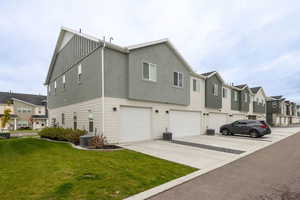 View of home's exterior with a residential view, driveway, a garage, a lawn, and board and batten siding