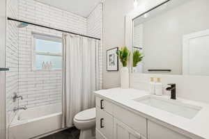 Full bathroom with shower / tub combo with curtain, vanity, and dark tile patterned flooring