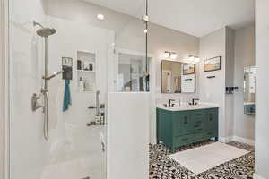 Bathroom featuring double vanity, a stall shower, and light tile patterned floors