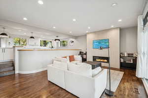 Living area with a large fireplace, recessed lighting, and dark wood-type flooring