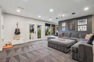 Carpeted living room with recessed lighting and french doors