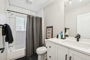 Bathroom featuring shower / bath combo with shower curtain, vanity, and tile patterned floors