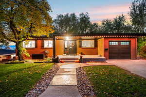 Ranch-style home featuring brick siding, a garage, driveway, and a front yard