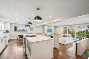 Kitchen with a center island, open floor plan, dark wood finished floors, white cabinetry, and recessed lighting