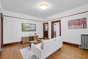 Living room featuring hardwood / wood-style floors, radiator, and a textured ceiling
