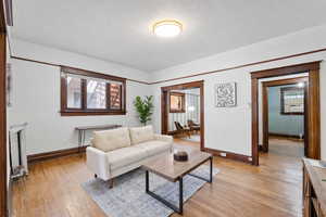 Living room featuring light wood-style floors, a textured ceiling, and a baseboard radiator