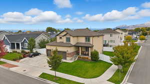 View of front of house with a residential view, stucco siding, driveway, stone siding, and roof with shingles