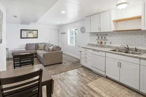 Kitchen with light countertops, backsplash, white cabinetry, white dishwasher, and recessed lighting