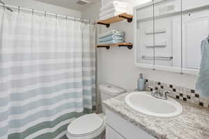 Full bath featuring curtained shower, vanity, and backsplash