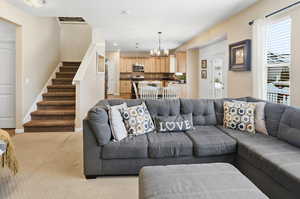 Living room with stairs, a chandelier, light colored carpet, and recessed lighting