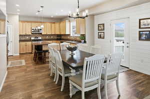 Dining area featuring healthy amount of natural light, a chandelier, dark wood-type flooring, and recessed lighting