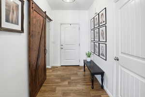 Hallway featuring dark wood-style floors and a barn door