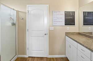 Full bathroom with wood finished floors, vanity, and a stall shower