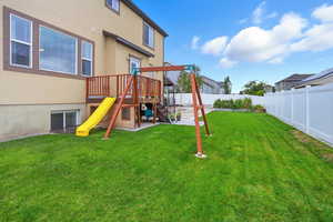 View of play area with a wooden deck and a fenced backyard
