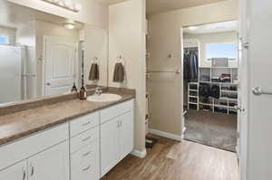Full bath with vanity, a walk in closet, light wood-style flooring, and curtained shower