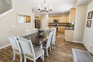 Dining room with a chandelier, dark wood finished floors, and recessed lighting