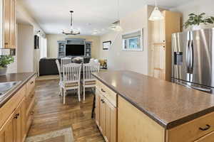 Kitchen featuring light brown cabinets,  dark countertops, a kitchen island, and open floor plan