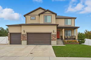 View of front of house with covered porch, stucco siding, stone siding, concrete driveway, and an attached garage