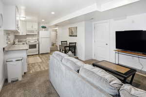 Living area with light carpet and recessed lighting