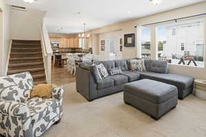 Living room featuring stairway, a chandelier, light wood-type flooring, recessed lighting, and light carpet