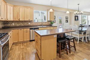 Kitchen with light brown cabinetry, decorative backsplash, and dark countertops