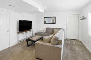 Carpeted living area with recessed lighting and baseboards