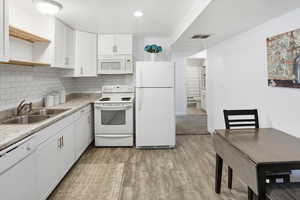Kitchen with white appliances, tasteful backsplash, light countertops, open shelves, and white cabinetry