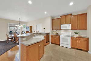 Kitchen with white appliances, light countertops, recessed lighting, a chandelier, and hanging light fixtures