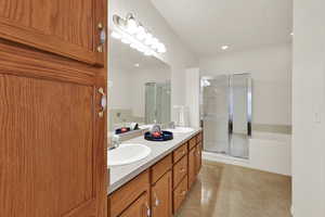 Full bathroom featuring a bath, double vanity, a stall shower, recessed lighting, and light tile patterned flooring
