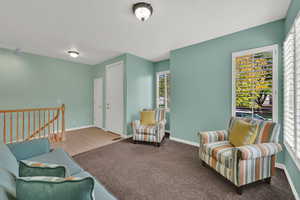 Living area featuring an upstairs landing, carpet floors, and tile patterned floors