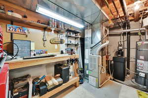 Unfinished basement with secured water heater, a water softener, a workshop area, and heating unit